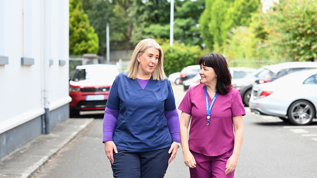 Eight nurses in uniforms and scrubs standing on stairs, facing camera